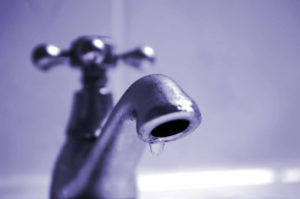 Close up photo of a leaky cheaper delta faucet in blue hue.