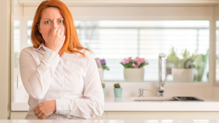 Woman disgusted by water that smells like rotten eggs, often caused by hydrogen sulfide (H2S) in hot water heaters or plumbing lines.