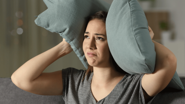 woman holding pillows over her ears