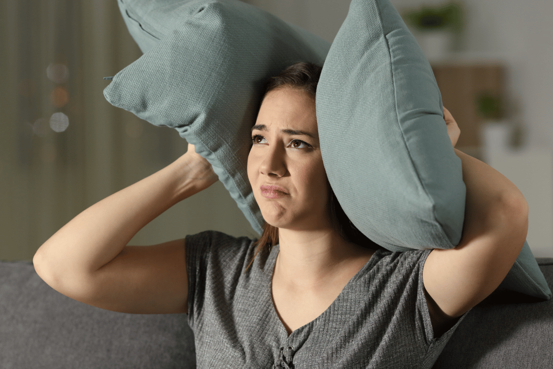 woman holding pillows over her ears