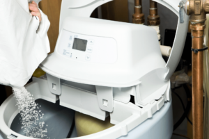 homeowner pouring salt pellets into water softener