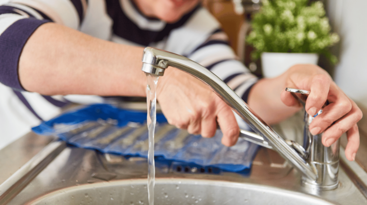 person repairing kitchen faucet with tools on counter