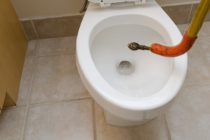 professional plumber using closet auger to clear clogged toilet