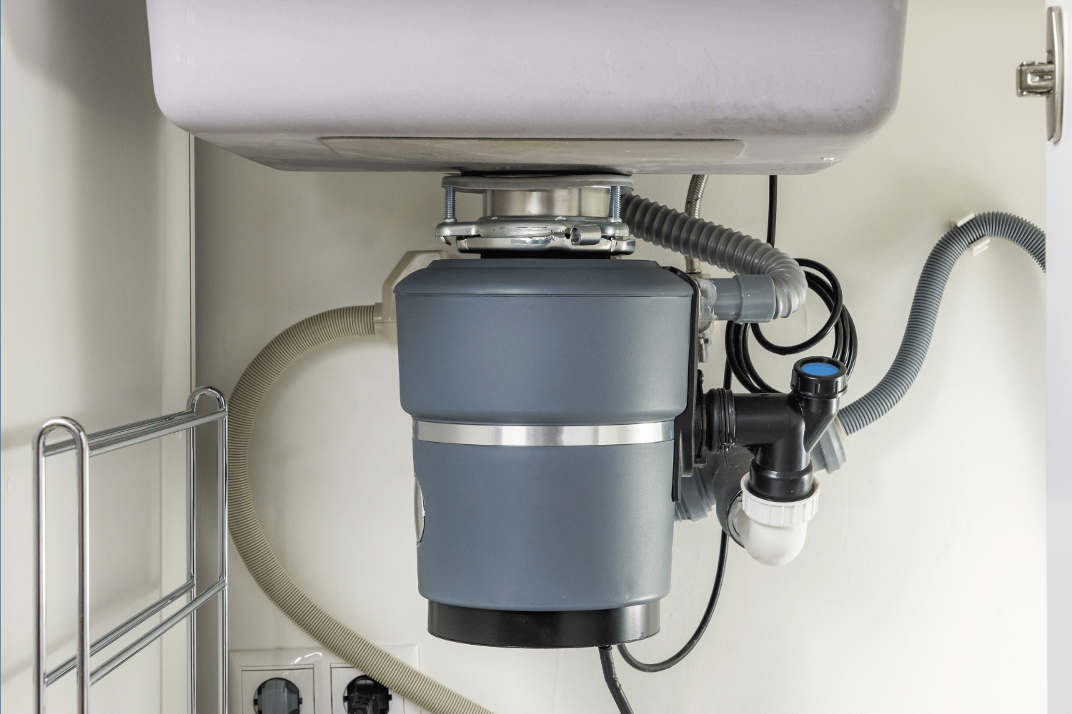 person putting potato peelings down garbage disposal in kitchen sink