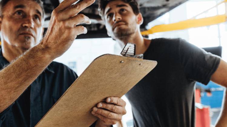 A professional plumber pointing out issues on an inspection clipboard to a homeowner, symbolizing regular plumbing maintenance and assessment.